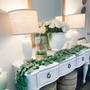 Macro detail of artificial eucalyptus garland draped over a white console table decor