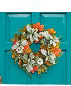 Close-up of fall wreath with white pumpkins and frosted leaves on a blue wooden door