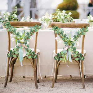 Close-up of Eucalyptus and white tulips with mint ribbons on wooden X-back wedding chairs