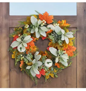 Close-up of fall wreath featuring white pumpkins and maple leaves on a rustic wooden door