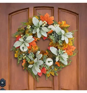 Detail of autumn wreath with faux pumpkins and maple leaves on a brown wooden door