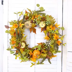Autumn wreath with pumpkins, maple leaves, and green berries on a white shutter background