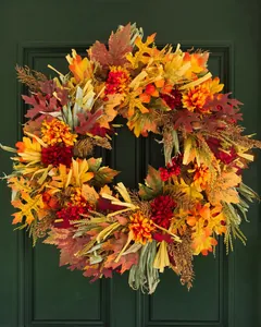 Detail of autumn wreath with maple leaves, berries and flowers on green wood door