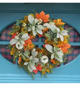 Detailed view of autumn wreath with maple leaves, white pumpkins and berries on door