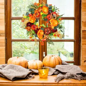 Detail of autumn wreath with pumpkins and roses hanging on a rustic wooden window frame