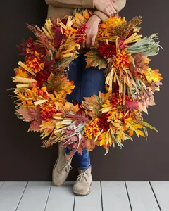 Close-up of autumn wreath with maple leaves berries and chrysanthemums held by model