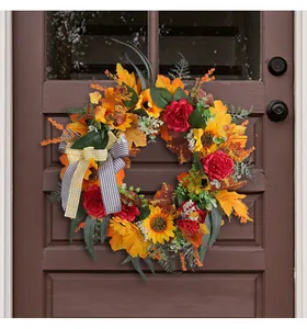 Close-up of autumn harvest wreath with sunflowers and bow on dark wood door