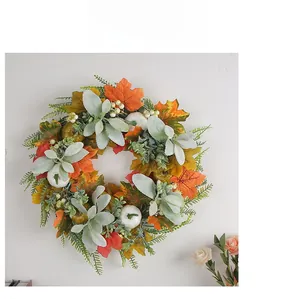 Detail of autumn wreath with maple leaves, white pumpkins and berries on a wall