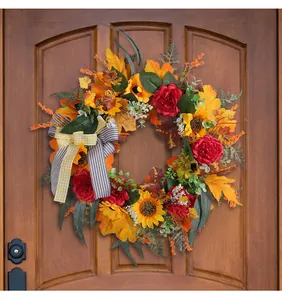 Detail of autumn harvest wreath with sunflowers, red peonies, and maples on a wooden door