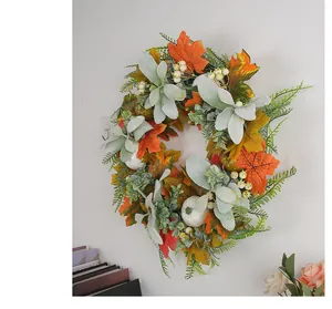 Close-up of fall wreath featuring white pumpkins, frosted maple leaves and white berries