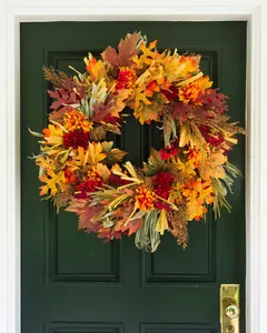 Close-up of fall wreath featuring maple leaves, berries, and corn husks on a green door