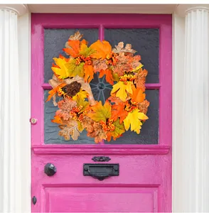 Close-up of autumn harvest wreath with maple leaves and berries on a pink door
