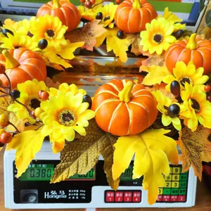 Detalle de una corona de otoño con calabazas y girasoles en una báscula que pesa 0,380 kg