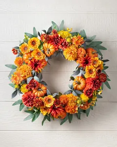 Close-up of fall wreath featuring orange sunflowers, red dahlias and realistic small pumpkins