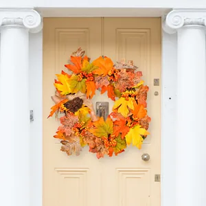 Autumn harvest wreath with maple leaves and red berries on a rustic wooden door