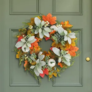 Autumn wreath with maple leaves and white pumpkins hanging on a modern green door