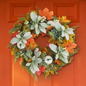 Autumn wreath featuring maple leaves and pumpkins displayed on an orange front door