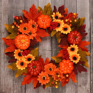 Close-up of autumn wreath with pumpkins, sunflowers, and maple leaves on grey wood