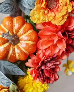 Detail of autumn wreath with orange pumpkins, warm silk dahlias and green eucalyptus leaves