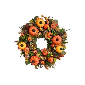 Golden fall wreath with artificial pumpkins, maple leaves and pine cones for harvest festival