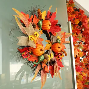 Corona de otoño con calabazas y hojas de arce decorada en una puerta de vidrio