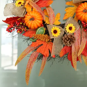 Detalle de corona de otoño con calabazas, hojas de arce, piñas y lazo de arpillera