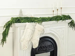 Detail von weißen Strick-Weihnachtssocken mit grüner Norfolk-Kieferngirlande