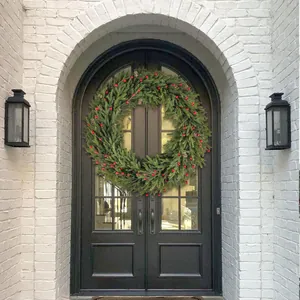 Close-up of 28 inch Christmas wreath with red berries and pine cones on a dark arched door
