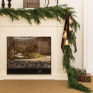 Close-up of lifelike cedar garland with vintage brass bells and brown velvet ribbon décor