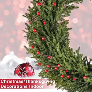 Close-up of artificial pine needles with red berries and pinecones for Christmas decor