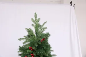 Detail of faux Christmas tree top with deep green pine needles and red berries