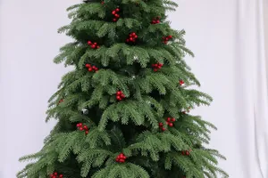 Close-up of realistic green pine branches and bright red berry decor on a Christmas tree