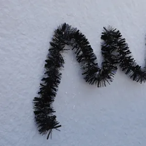 Glossy black Christmas tinsel garland for party decoration on a textured grey background
