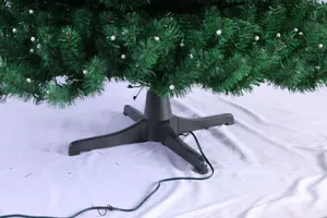 Détail des branches de sapin de Noël en PE avec points blancs et base de support en croix