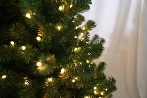 Gros plan d'aiguilles de sapin artificiel avec guirlandes lumineuses LED blanc chaud