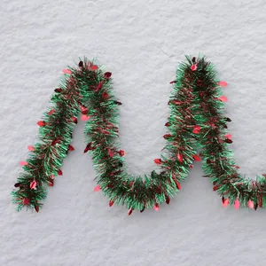 Red and green Christmas tinsel garland with holly leaf accents for holiday party decor