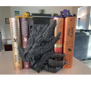 Détail d'un serre-livres en forme de tête de dragon noir mat parmi des livres de fantasy