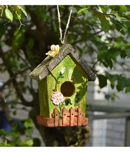 Detail of green resin birdhouse with 3D flower and butterfly hanging on a tree branch