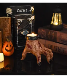 Realistic severed hand candle holder with skull relief and burning tea light candle