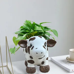 Detail view of a cute resin cow planter with green plants on a minimalist desk