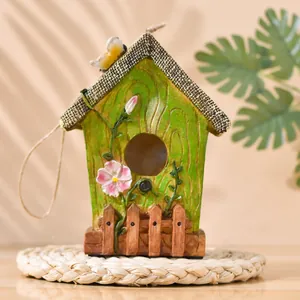 Garden bird house figurine with pink flowers and green vines on rustic wooden fence base
