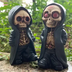 Pair of miniature Halloween reaper skull figurines in black robes on stone background