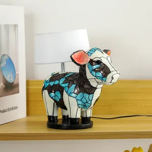Colorful mosaic bull table lamp with white shade on a wooden shelf, modern resin art decor