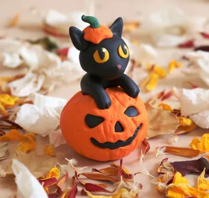 Detail of handcrafted resin black cat wearing pumpkin hat on a carved Halloween pumpkin