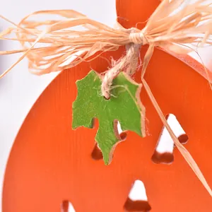 Handcrafted wooden pumpkin ornament with raffia bow and leaf detail for Halloween decor
