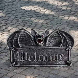 Macro detail of Gothic bat welcome plaque with stone texture and small skulls
