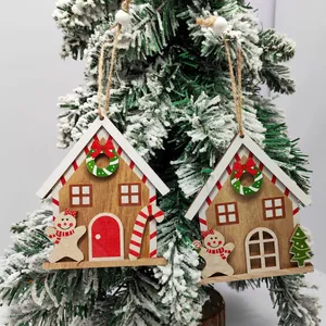 Detail of wooden gingerbread house ornaments hanging on a snowy Christmas tree