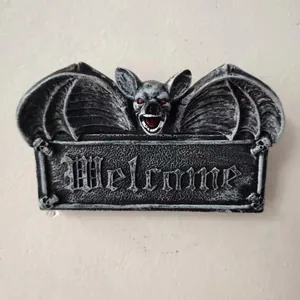 Detailed view of Gothic bat welcome sign with red eyes and skull resin carvings