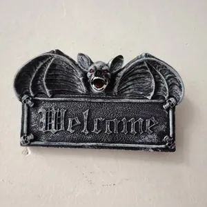 Close-up of Gothic resin bat welcome sign with red eyes and skull details