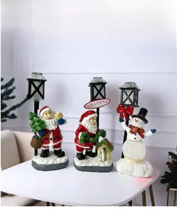 Detailed view of resin Santa and Snowman figurines next to a lighted Welcome lamp post